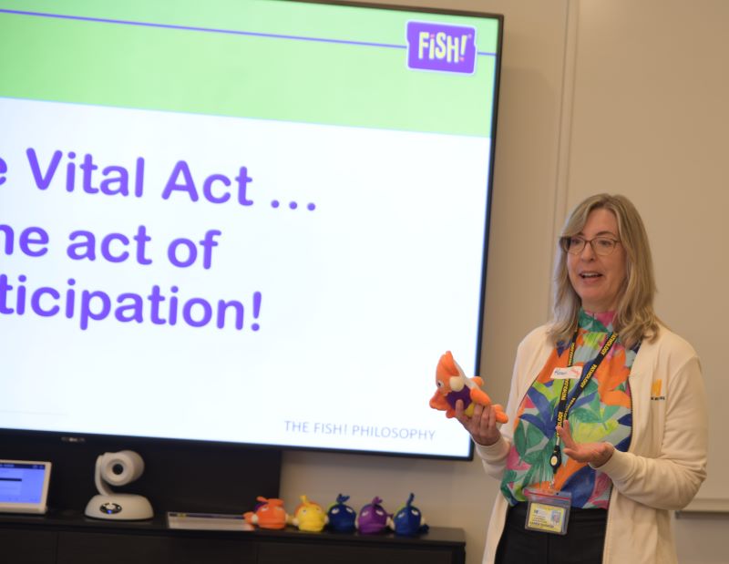 Karen Barron prepares to throw "Pete the Perch", the FiSH! mascot.